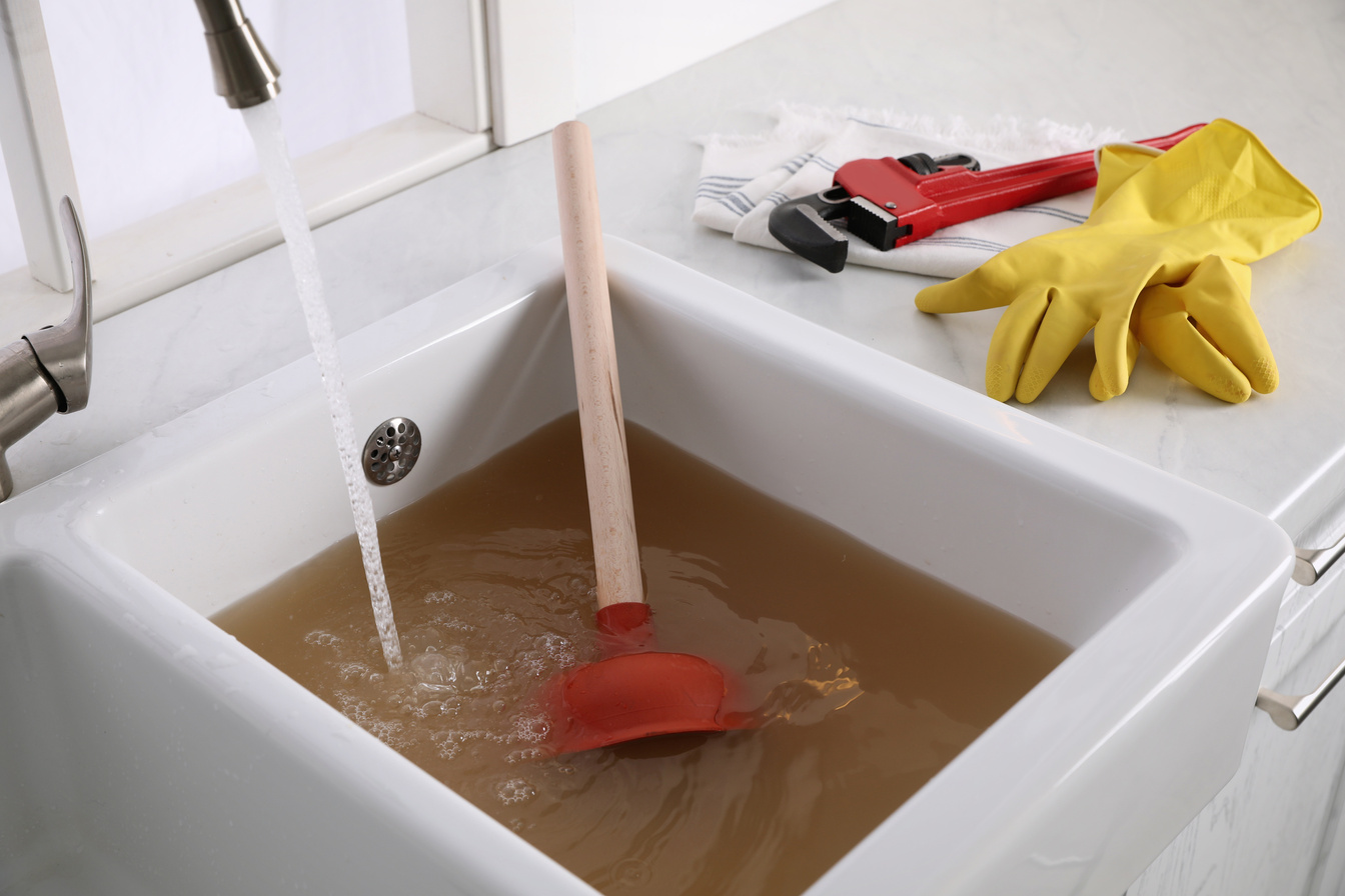 Kitchen Counter with Clogged Sink, Plunger and Plumber's Accesso